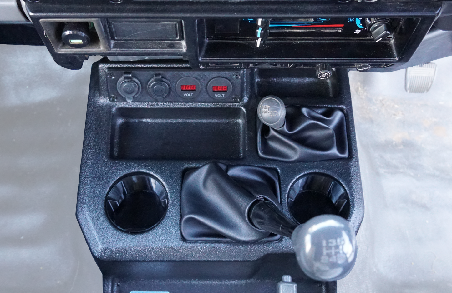 Close-up of a car's center console with gear shift and cup holders.